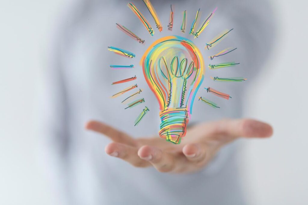 Hand mit einer darüber gezeichneten Glühbirne als Symbol für Wissen, Erfahrung, Idee und Information rund um das Thema Autismus, ADHS und Neurodivergenz