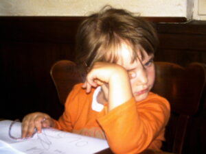 Autismus Diagnose im Erwachsenenalter: Kinderfoto von Marlene reizüberflutet in einem Restaurant. Sie reibt sich müde und die Augen.