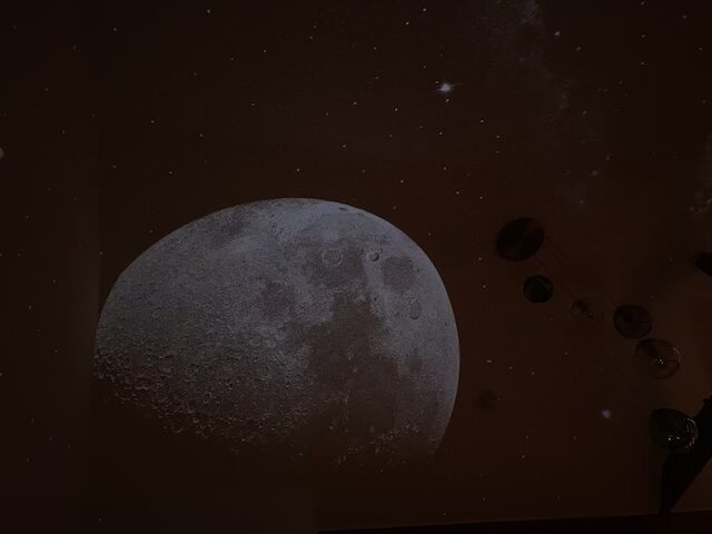 Leben mit AuDHD: Zu sehen ist ein Foto des Sternenhimmel-Projektors von Marlene. Die Projektion eines Mondes und vielen Sternen ist an ihrer Decke zu sehen.