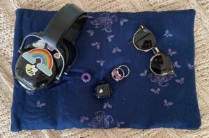 Unmasking: Foto von Marlene´s gewichtetem Kissen, ihren Kopfhörern, ihrer Sonnenbrille und Fidgets.