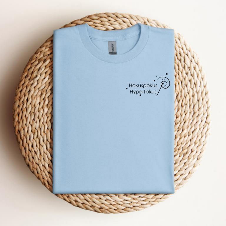 Gefaltetes T-Shirt mit minimalistischer Zauberstab-Grafik und dem Schriftzug „Hokuspokus Hyperfokus“ – humorvolles Design für ADHS & Neurodivergenz.