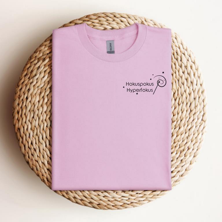 Gefaltetes T-Shirt mit minimalistischer Zauberstab-Grafik und dem Schriftzug „Hokuspokus Hyperfokus“ – humorvolles Design für ADHS & Neurodivergenz.