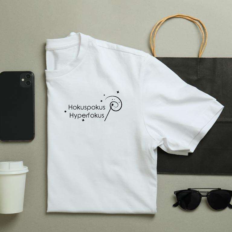 Gefaltetes T-Shirt mit minimalistischer Zauberstab-Grafik und dem Schriftzug „Hokuspokus Hyperfokus“ – humorvolles Design für ADHS & Neurodivergenz.