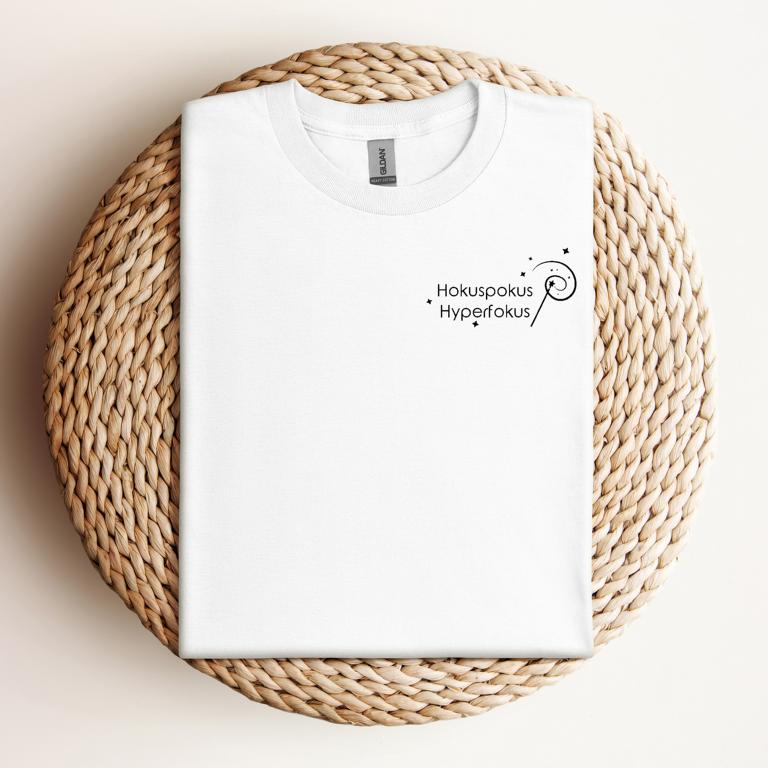 Gefaltetes T-Shirt mit minimalistischer Zauberstab-Grafik und dem Schriftzug „Hokuspokus Hyperfokus“ – humorvolles Design für ADHS & Neurodivergenz.