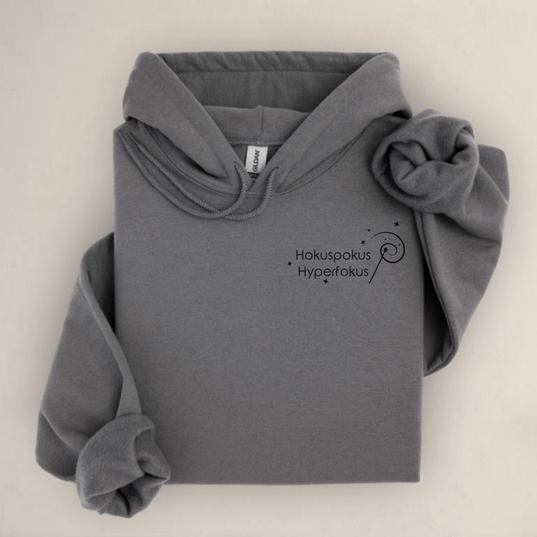 Gefalteter Hoodie mit minimalistischem Aufdruck „Hokuspokus Hyperfokus“ und Zauberstab-Illustration – humorvolles Statement für ADHS, AuDHD und Hyperfokus.