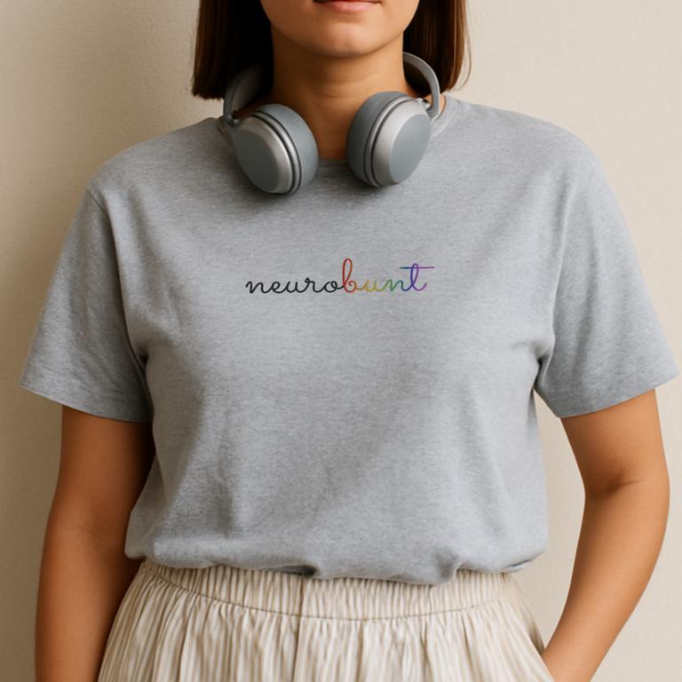 Gefaltetes T-Shirt mit handschriftlichem Aufdruck „neurobunt“ – minimalistisches Design für neurodivergente Menschen und neuroaffirmative Mode.