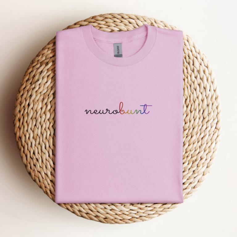 Gefaltetes T-Shirt mit handschriftlichem Aufdruck „neurobunt“ – minimalistisches Design für neurodivergente Menschen und neuroaffirmative Mode.