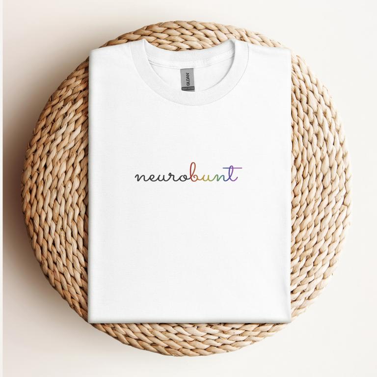 Gefaltetes T-Shirt mit handschriftlichem Aufdruck „neurobunt“ – minimalistisches Design für neurodivergente Menschen und neuroaffirmative Mode.