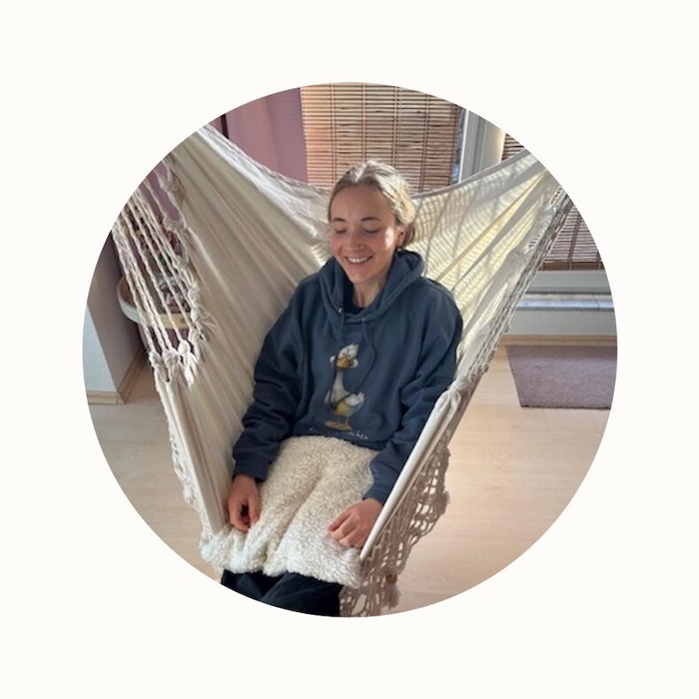 Marlene im Hängesessel mit ihrem Gewichtskissen zur sensorischen Regulation bei Autismus und ADHS in beige auf dem Schoß